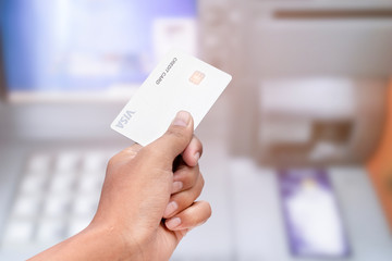 Hand holding credit card, using an atm machine.