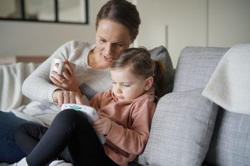 Obraz premium Mother and young daughter playing games on child's tablet at home