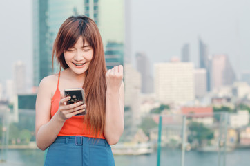 Euphoric woman watching her smart phone over city background