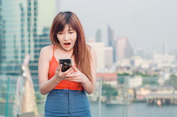 Close up portrait anxious young girl looking at phone seeing bad news or photos with disgusting emotion on her face over outside city background.