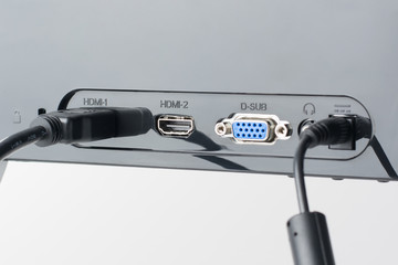 Back pannel of the monitor with different ports. HDMI and power cables are plugged. Old VGA port is...