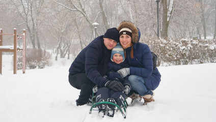 Fototapeta na wymiar Family portrait in the winter park with charming kid.