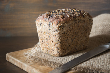 Loaf of fitness rye bread with ears of wheat on wooden board. Space for text.