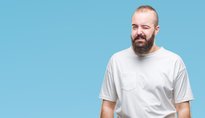 Young caucasian hipster man wearing casual t-shirt over isolated background winking looking at the camera with sexy expression, cheerful and happy face.
