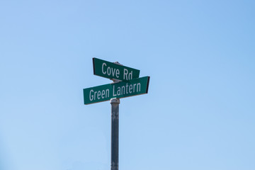 Street sign Cove Rd and Green Lantern on metal post with blue background