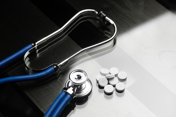 Stethoscope and pills are on the black table