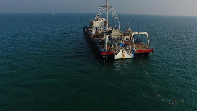 drone view of an oil rig submarine cable station laying cables at the bottom of the sea with a nice sun