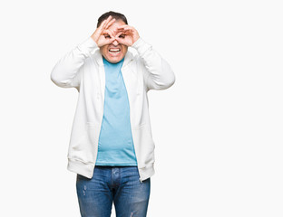 Middle age arab man wearing sweatshirt over isolated background doing ok gesture like binoculars sticking tongue out, eyes looking through fingers. Crazy expression.