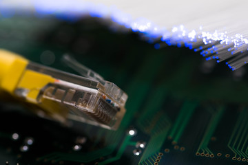 Yellow internet switch on computer circuit board, glowing optical fibres on the background.