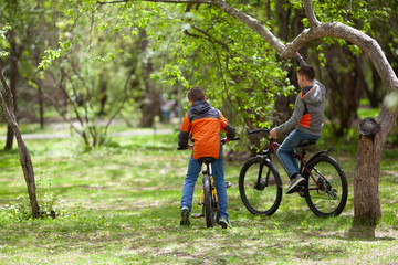 Obraz premium Brothers ride bicycles in summer park