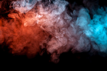 Clouds of isolated colored smoke: blue, red, orange, pink; scrolling on a black background in the dark close up.