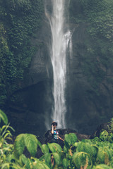 Obraz premium Young woman posing on a great Sekumpul waterfall in the deep rainforest of Bali island, Indonesia.
