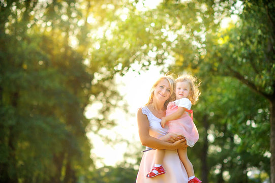mother with her little daughter in her arms in a beautiful park at sunset