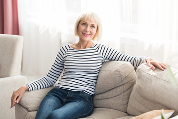 Obraz premium Cheerful senior woman feeling happy and relaxed, sitting on couch