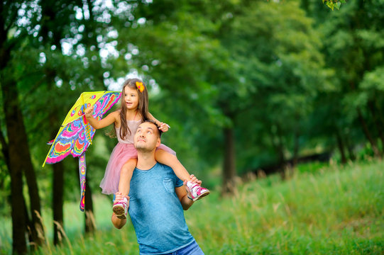 dad and little daughter are walking in the spring park, flying a kite and having fun