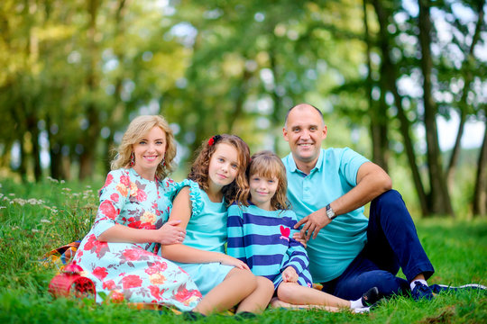happy family in a beautiful autumn park sitting on the grass hugging and smiling