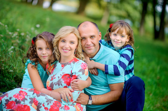 happy family resting in nature sitting on the grass hugging and laughing