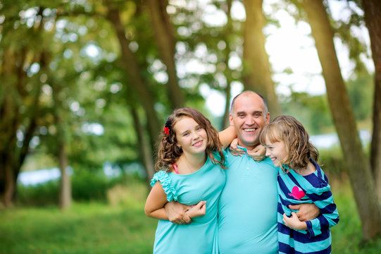 dad with two daughters in the park, hugging and playing
