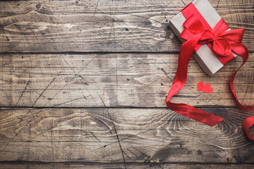Fototapeta na wymiar Concept Valentine's Day. Gift box with red bow on wooden table. copy space