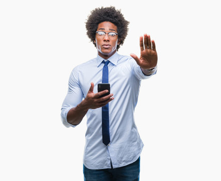 Afro american business man texting using smartphone over isolated background with open hand doing stop sign with serious and confident expression, defense gesture