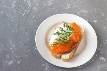 Sandwich with cheese and trout on a white plate.
