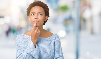 Young beautiful african american woman wearing a sweater over isolated background with hand on chin thinking about question, pensive expression. Smiling with thoughtful face. Doubt concept.