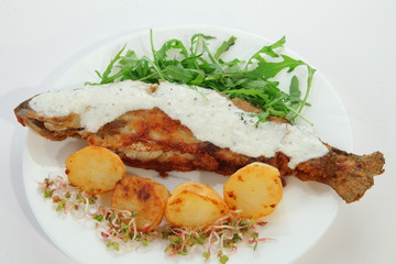 grilled sea fish with potatoes on white plate