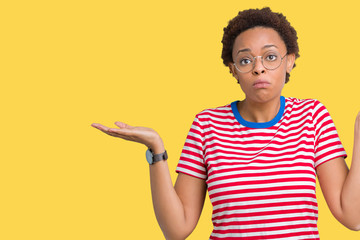 Beautiful young african american woman wearing glasses over isolated background clueless and...