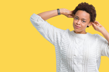 Beautiful young african american woman wearing sweater over isolated background Smiling pulling ears with fingers, funny gesture. Audition problem