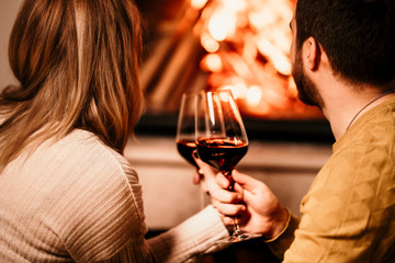 In love people having a glass of wine by the fireplace and enjoying a lovely evening at home