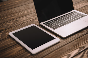 digital tablet and laptop with blank screens on wooden table