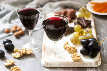 Creme de Cassis homemade liqueur served with grapes, nuts and chocolate. Rustic style.