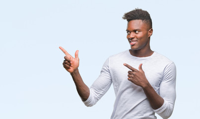 Young african american man over isolated background smiling and looking at the camera pointing with two hands and fingers to the side.