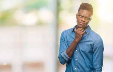 Young african american man over isolated background with hand on chin thinking about question, pensive expression. Smiling with thoughtful face. Doubt concept.