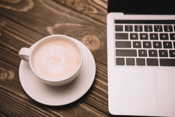 cup of coffee and laptop on wooden table
