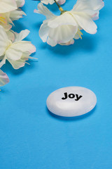 White flowers with a stone that depicts  joy.