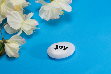 White flowers with a stone that depicts  joy.