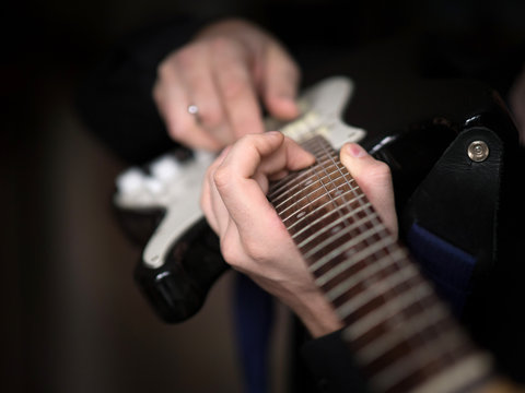 Male hands playing on electric guitar, close up, selected focus
