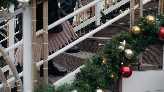 Christmas morning. house entrance decorated for holidays people leg man foot boots going up on stairs. Christmas decoration. garland of fir tree branches and lights on the railing