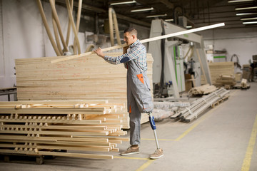 Disabled young man with an artificial leg is working at the furniture  factory