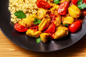 Mexican cuisine. Rice with black sesame. Spicy chicken with curry, paprika, cherry tomatoes and honest. Red Salsa Sauce Serve in a black plate, near spices. Recipe Background Image. top view