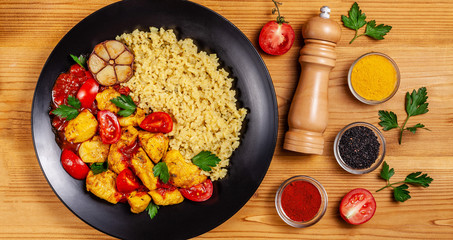 Mexican cuisine. Rice with black sesame. Spicy chicken with curry, paprika, cherry tomatoes and honest. Red Salsa Sauce Serve in a black plate, near spices. Recipe Background Image. top view