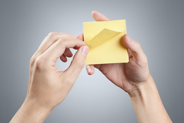 Hands holding a stack of yellow stickers on gray background