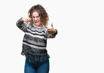 Beautiful brunette curly hair young girl wearing glasses over isolated background approving doing positive gesture with hand, thumbs up smiling and happy for success. Looking at the camera