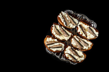 Sandwich with sprats, eggs and mayonnaise on black background.