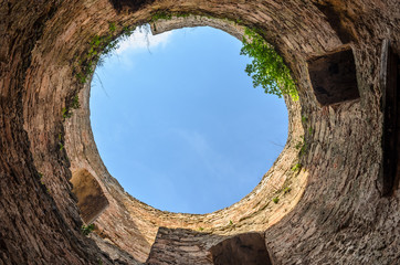 Circular panorama. Head spin. View up from the dilapidated medieval tower in the castle - the fortress of Eastern Europe. View of the sky, and around the stone well and ancient masonry. Ackermann.