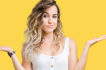 Young beautiful blonde woman over isolated background clueless and confused expression with arms...