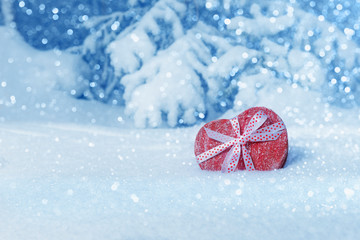 Fototapeta na wymiar Heart shaped red gift box in snowy forest