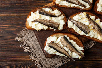 Sandwich with sprats, eggs and mayonnaise on wooden background.