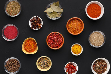 Assortment of spices in bowls on black background